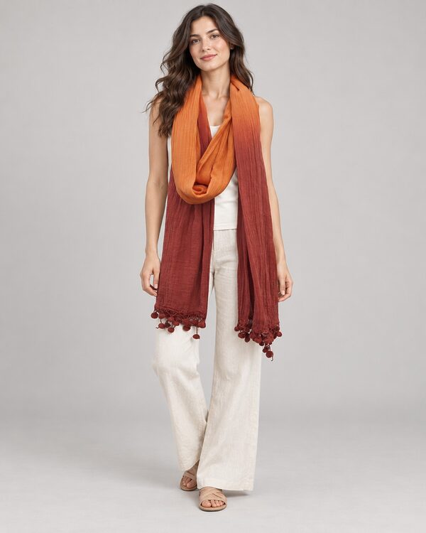 Orange to rust ombre linen scarf with pom-poms worn by a model, KK Fashion Exports