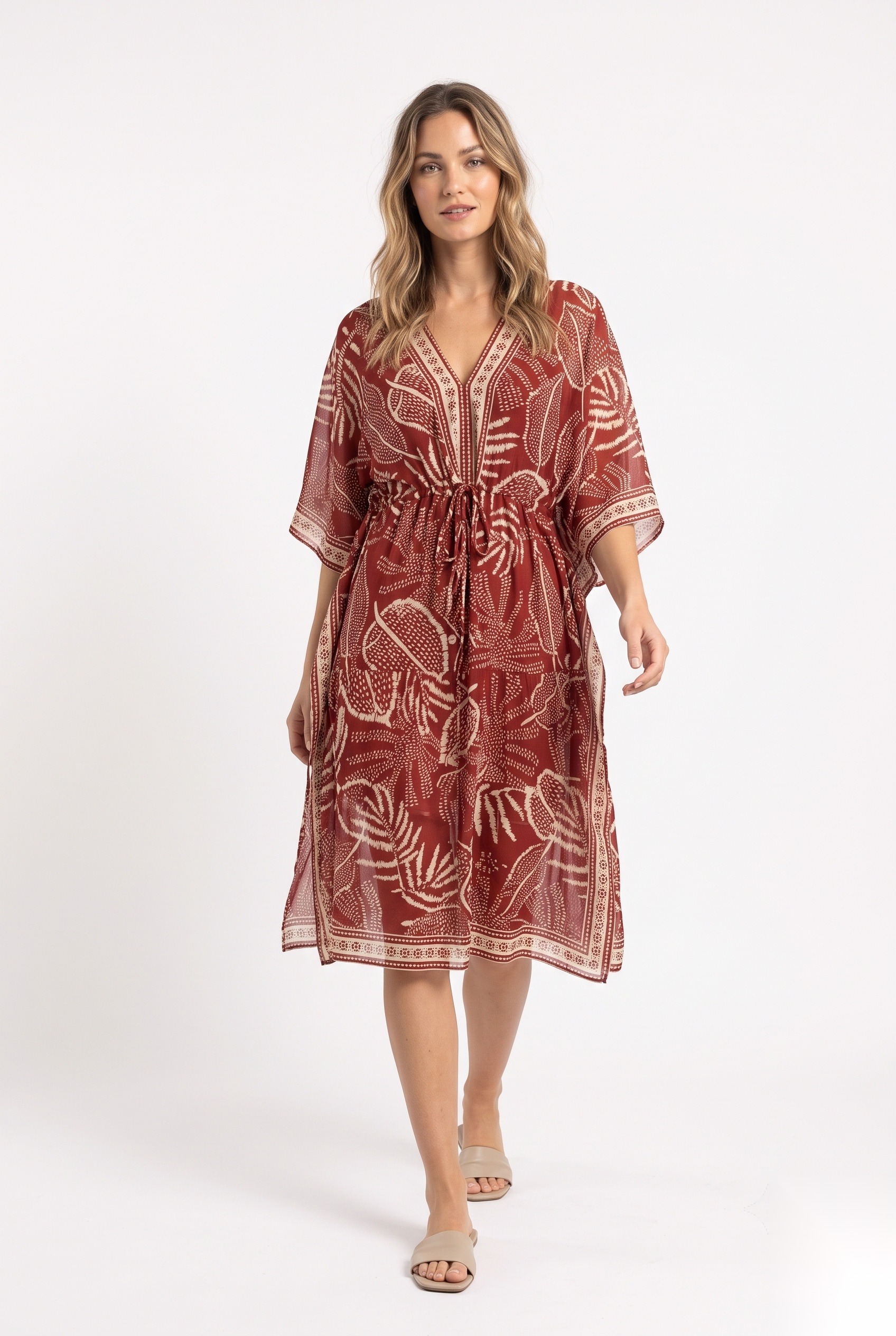 Knelang kaftan i sjifong med snøring i midjen i et tett tropisk bladverk med åreblader og dekorativ kantlist.