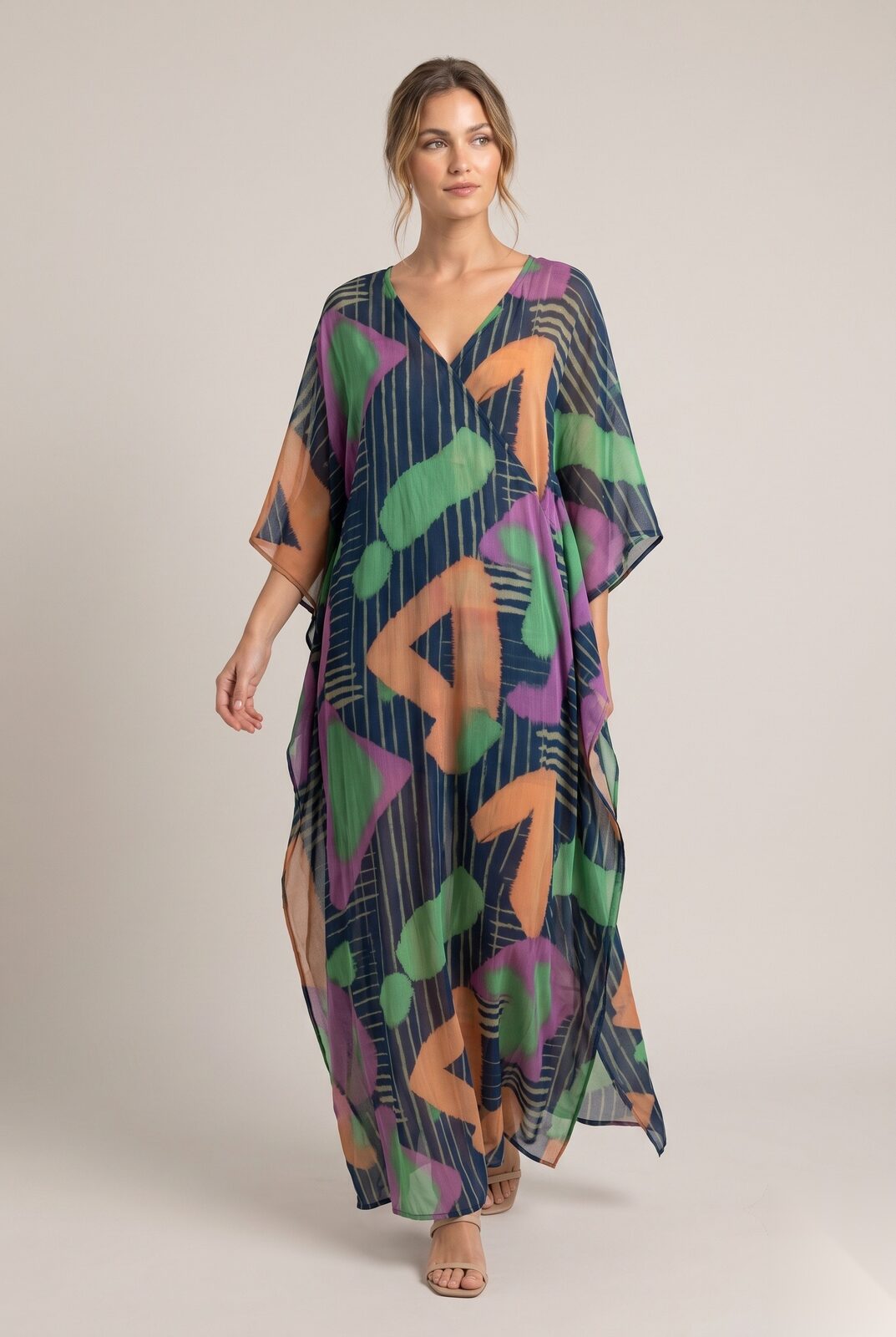 Lang kaftan i sjifong med V-hals og vide ermer i en stripete bakgrunn med store, maleriske, geometriske former.