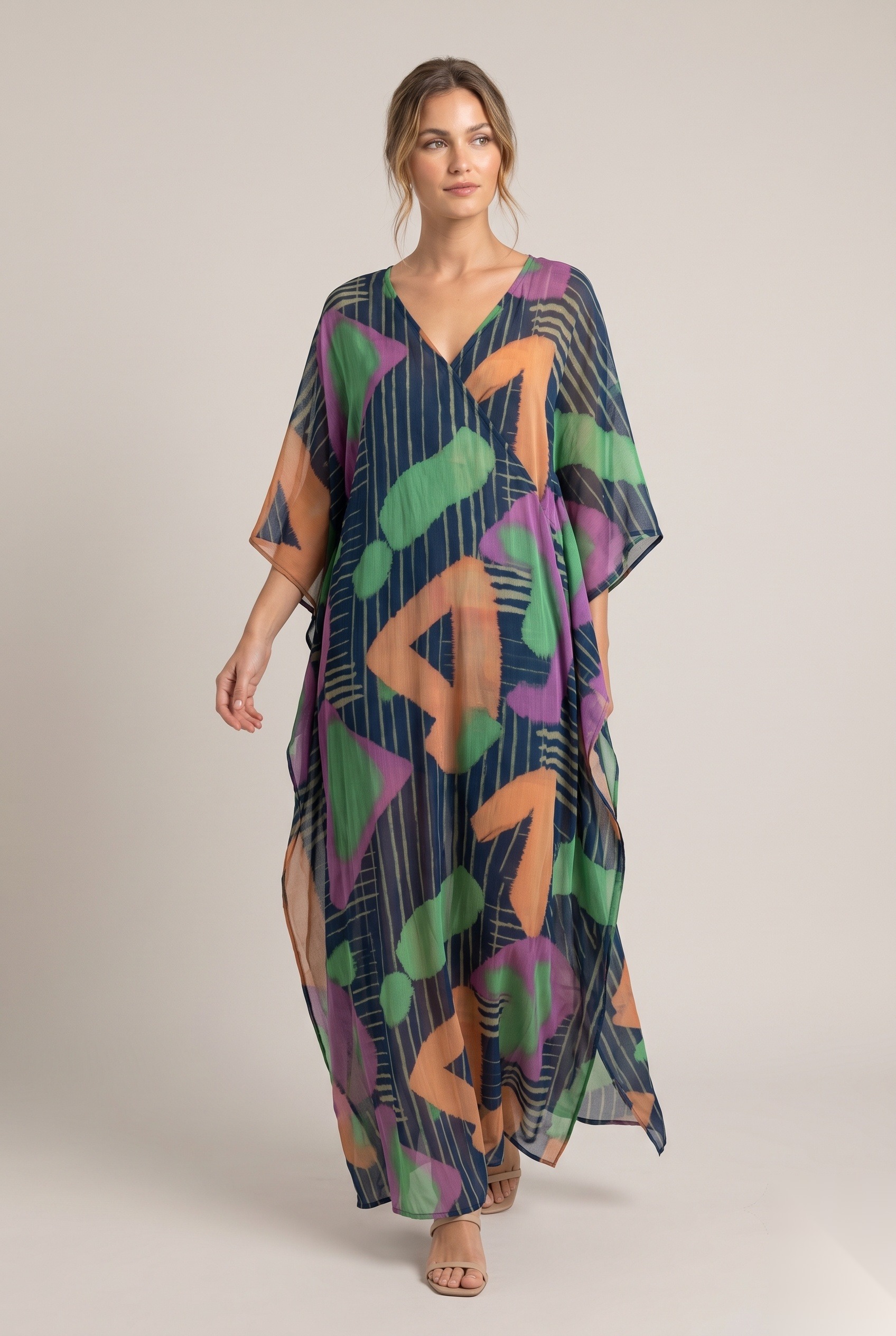 Lang kaftan i sjifong med V-hals og vide ermer i en stripete bakgrunn med store, maleriske, geometriske former.