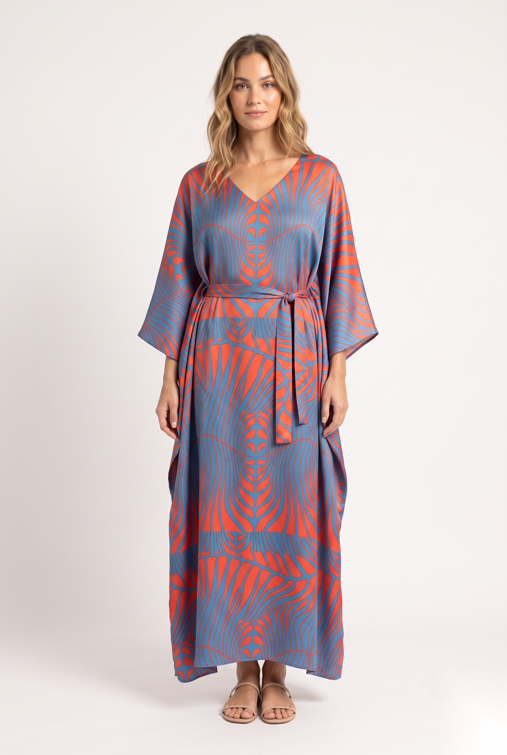 Bältad maxikaftan i satin med ett symmetriskt optiskt konsttryck av strålande chevronvågor i linjegrafik.