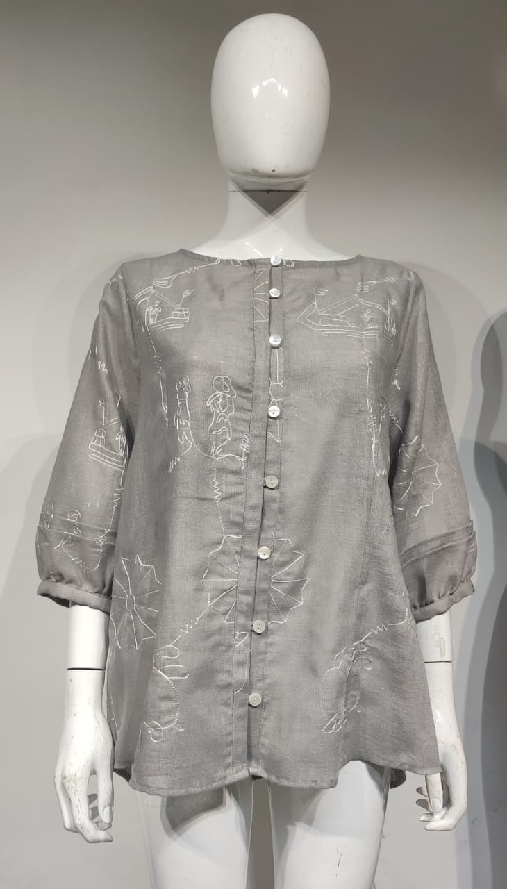 Grå mönstrad topp i polyester med knäppning framtill på en docka