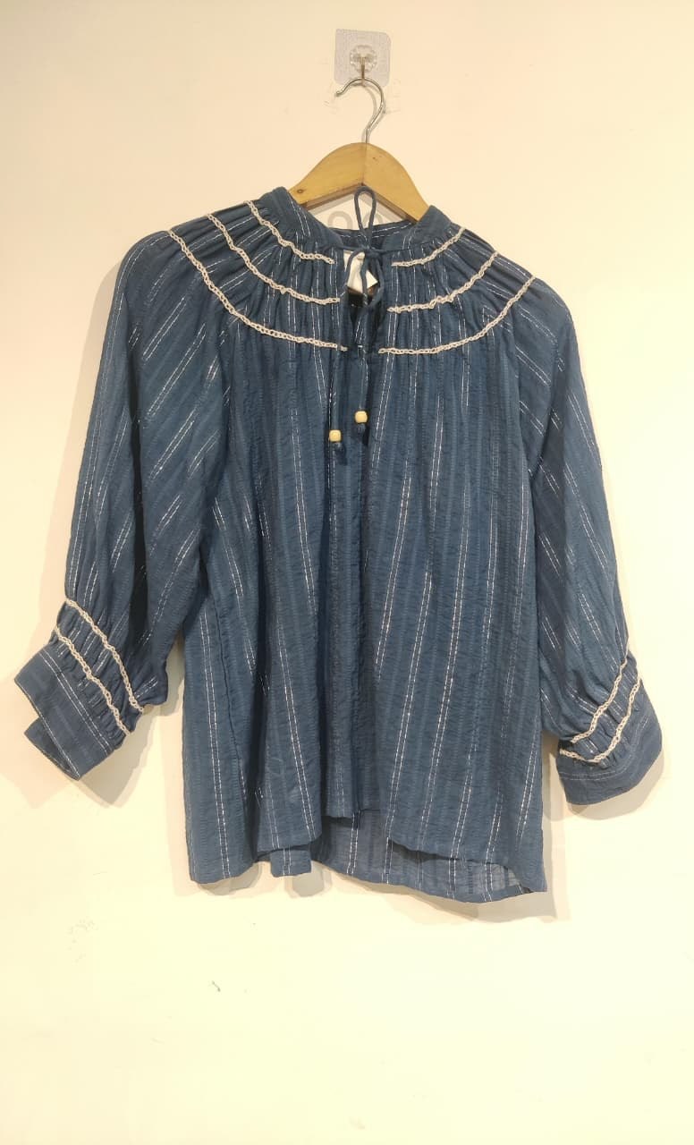 Blue cotton jacquard top with embroidered trims on a hanger