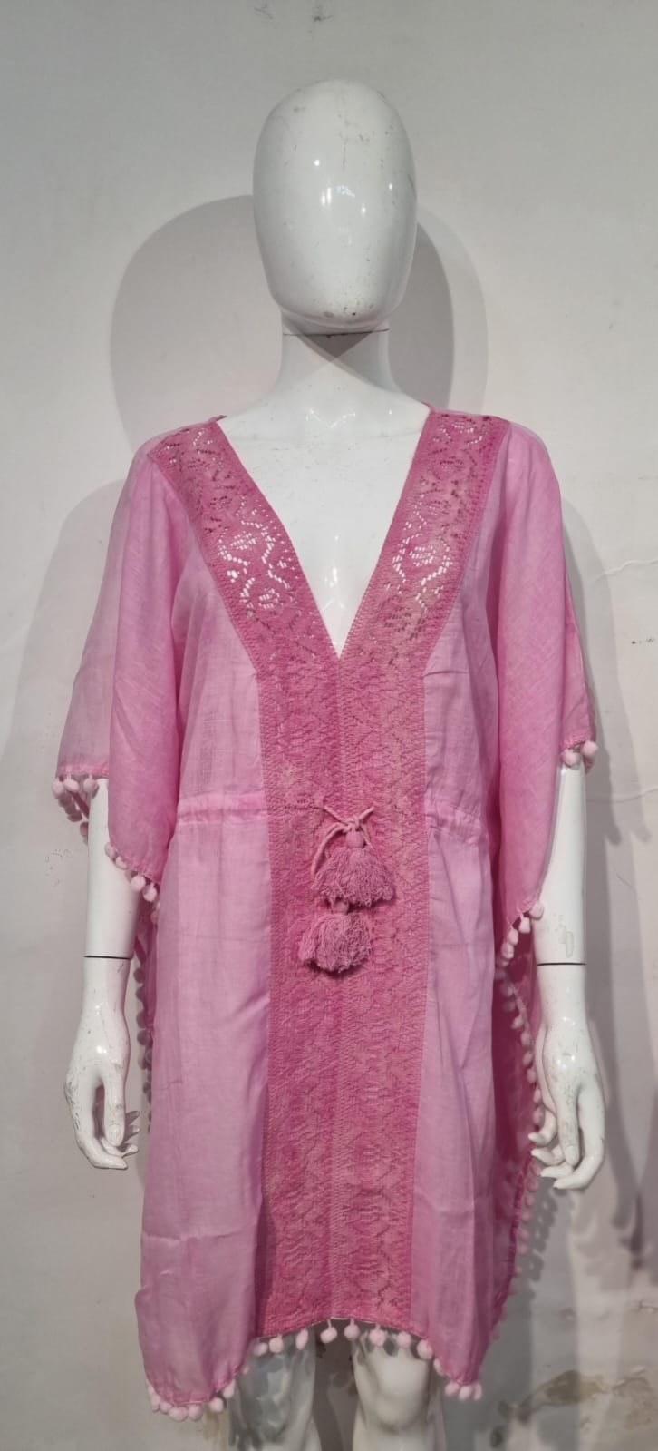 Pink lace kaftan beach dress with pom pom trim on a mannequin