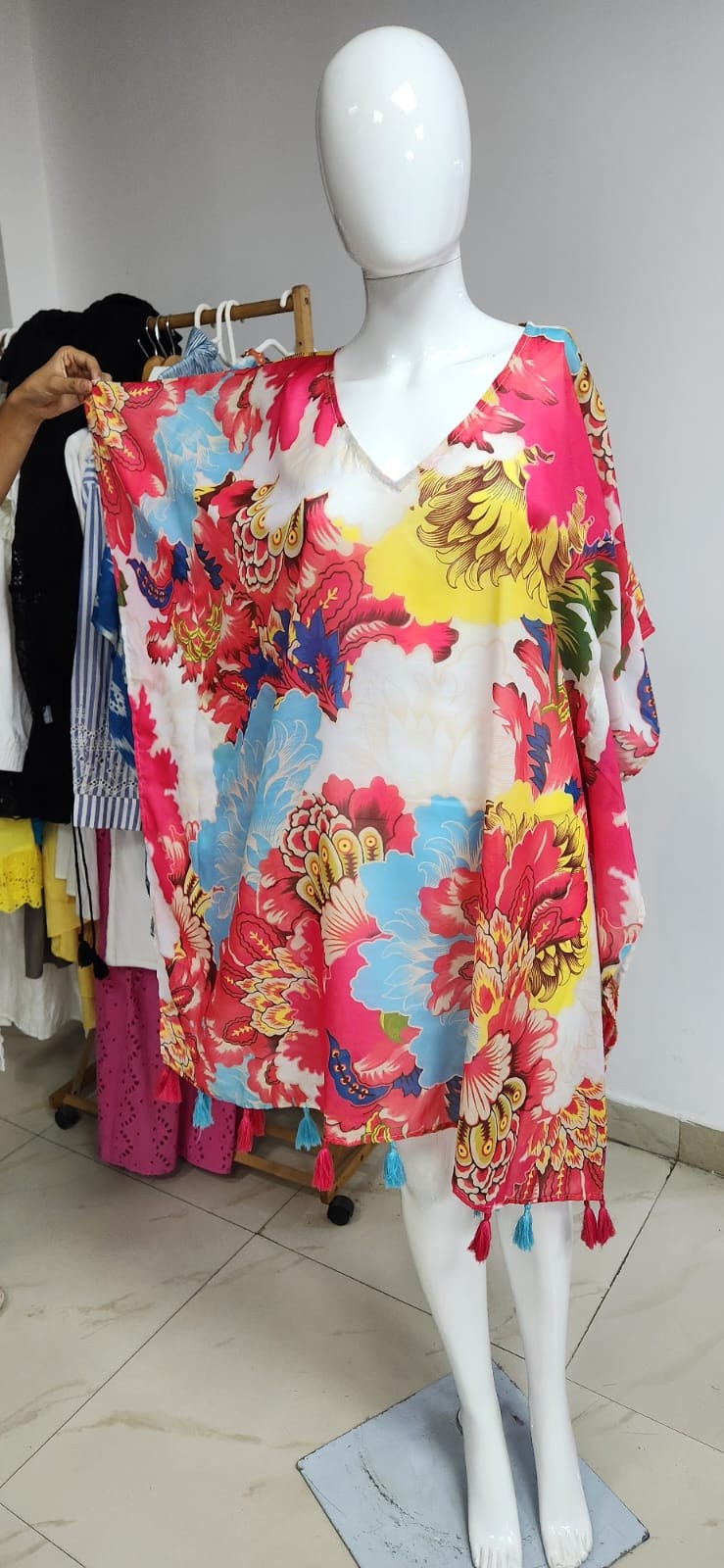 Bright floral kaftan with tasselled edges on a mannequin