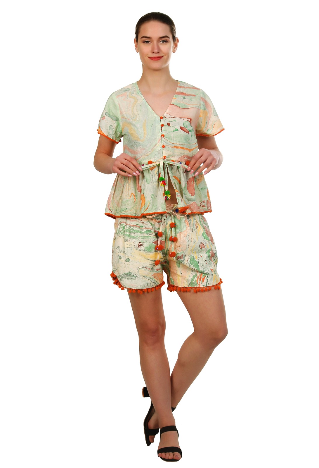 Woman in a marbled print cotton co-ord set of a tie-front top and shorts with orange pom-pom trim