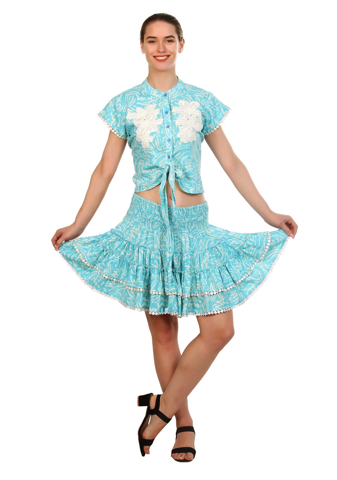 Woman in a turquoise printed co-ord set of a tie-front shirt top with lace flowers and a tiered skirt