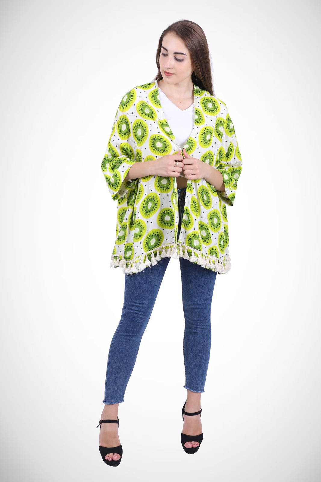 Woman in a green kiwi print kimono with a tasselled hem, worn open over a white top and jeans