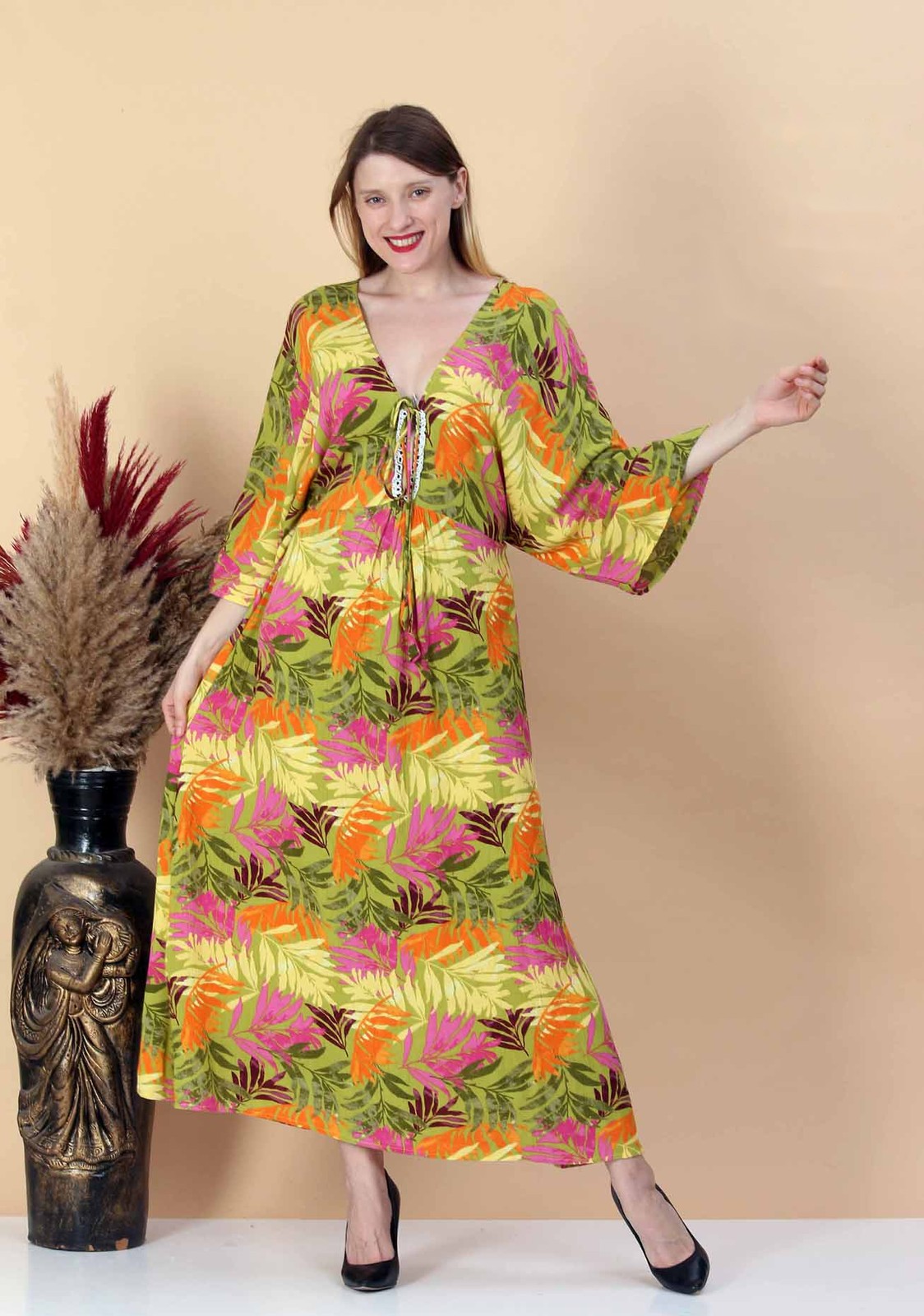 Woman in a viscose maxi dress with a green, pink and orange tropical leaf print